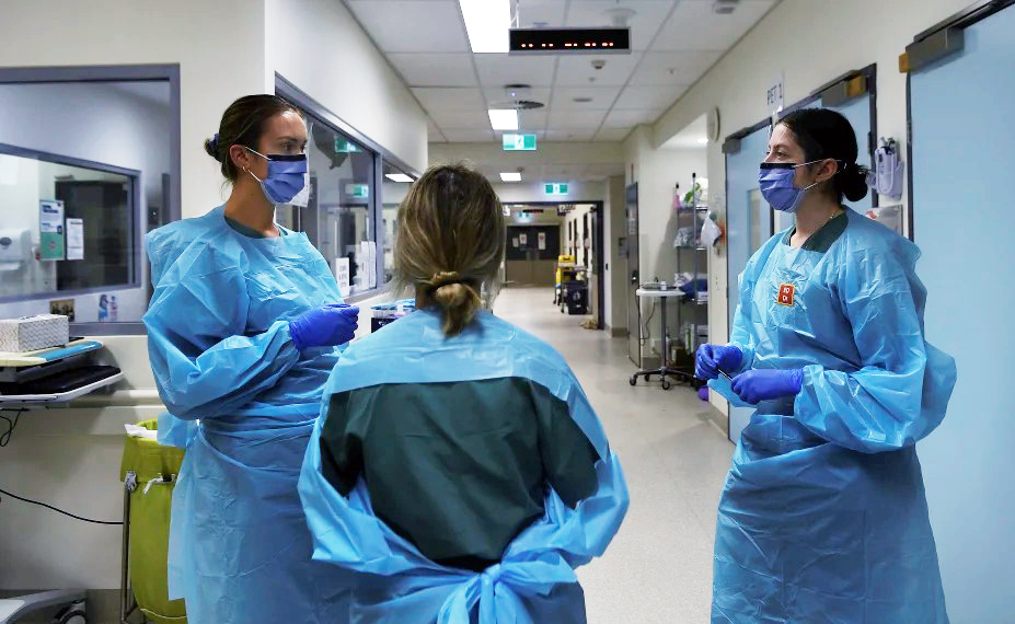 Three Nurses Wearing PPE At A Hospital Ward